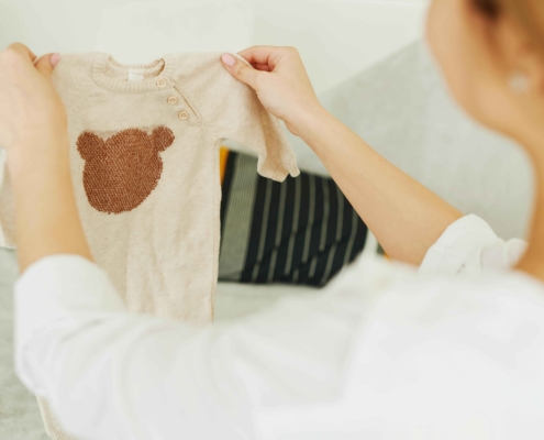 Celebrating the miracle of life: A woman lovingly holds a tiny onesie, symbolizing the precious new life made possible through her generous egg donation, bringing hope and happiness to intended parents and families affected by infertility.