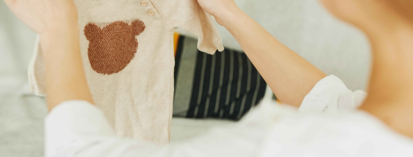 Celebrating the miracle of life: A woman lovingly holds a tiny onesie, symbolizing the precious new life made possible through her generous egg donation, bringing hope and happiness to intended parents and families affected by infertility.